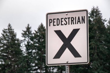 Yoldaki yaya geçidi tabelasını kapatın. Arka planda orman var. Courtenay, Kanada.