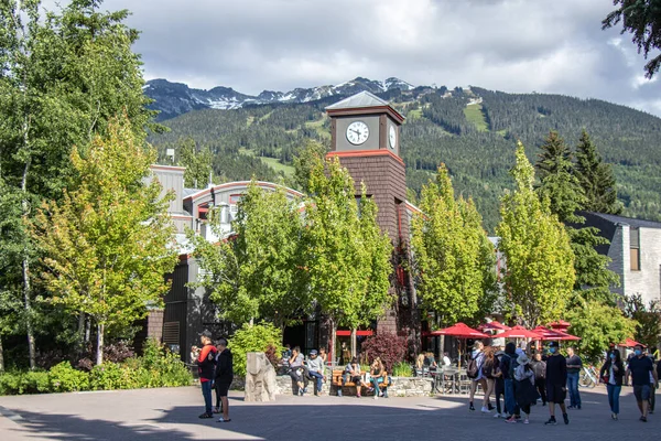 Whistler, Kanada - 5 Temmuz 2020: Güneşli bir günde arka planda dağ manzaralı Whistler Village dolusu insan. Seçici odak