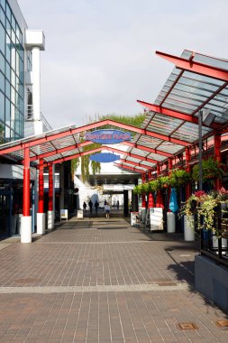 Vancouver, Kanada - 25 Eylül 2025: Kuzey Vancouver 'daki Quayside Plaza girişi: Cam çatılı kırmızı çelik kubbe, eğrelti otları, tuğla kaldırımlarda gezinen yayalar