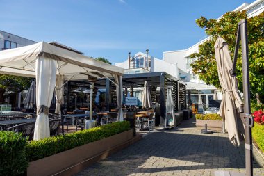 Vancouver, Kanada - 6 Ekim 2025: Granville Adası açıkhava veranda restoranı beyaz tente şemsiyeleri, masalar, sandalyeler, çitler, ağaçlar