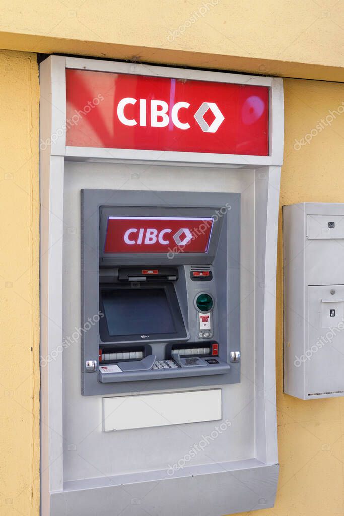 Vancouver, Canada - Oct 6,2025: CIBC bank ATM machine with red logo mounted in white alcove on yellow wall with white security panel at Granville Island