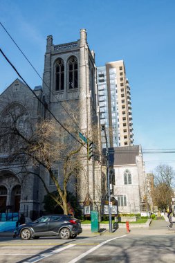 Vancouver, Kanada - 2 Mart 2026: St. Andrew 's Wesley Birleşik Kilisesi Gotik taş kulesi kemerli pencereli modern konut kulesi