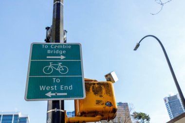 Vancouver, Kanada - 2 Mart 2026: Cambie Köprüsü ve West End 'e giden güzergahları gösteren yol işareti, sarı geçiş sinyalinin yanına monte edilmiş bisiklet sembolü