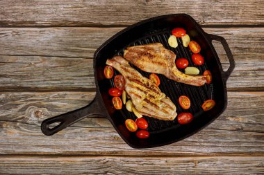 Ahşap zeminde ızgara domuz bifteği ve demir tava. Üst görünüm.