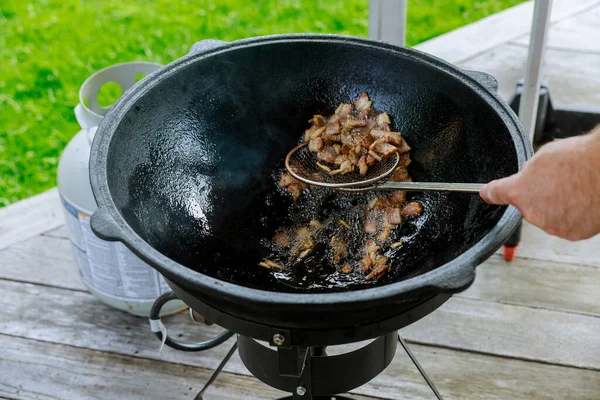 一个男人在外面的大锅里煮熏肉 野餐食品 — 图库照片