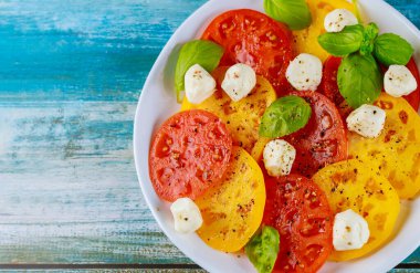 Beyaz tabakta fesleğen ve mozzarella ile dilimlenmiş domates. Kapatın. Üst görünüm.