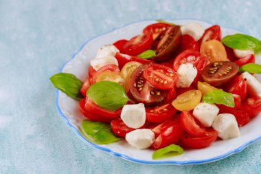 Beyaz tabakta mozarella peynirli vejetaryen salatası. Kapat..