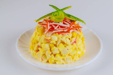 Beyaz tabaktaki yengeç salatası beyaz izole edilmiş arka planda salatalıkla süslenmiş..