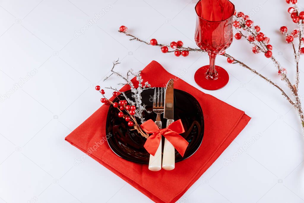 Christmas table dinnerware setting with red berry decorations on white background.
