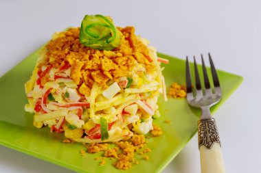 Yengeç çubuklu salata, salatalık, yumurta ve çatallı mısır cipsi..