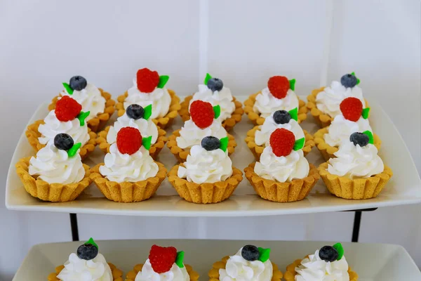 Tartlets mini dessert with fresh fruits on cake tiered stand.