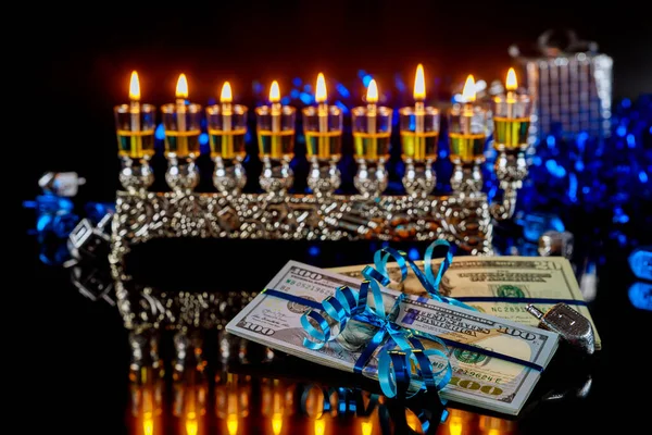 Dollar bill, cash gift with burning menorah for Hanukkah. Jewish holiday.