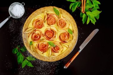 Siyah arka planda bıçak olan gül şeklinde elmalı turta. Üst görünüm.