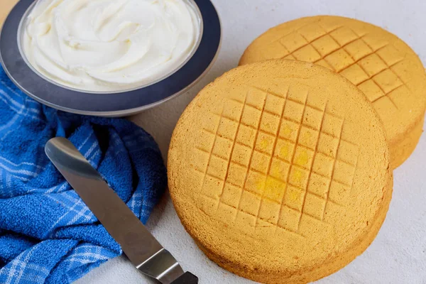 Sponge cake, frosting and spatula for making wedding cake.