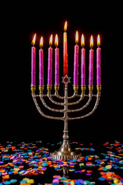 Pembe yanan mumlarla dikey menorah ve Yahudi bayramı için konfeti..