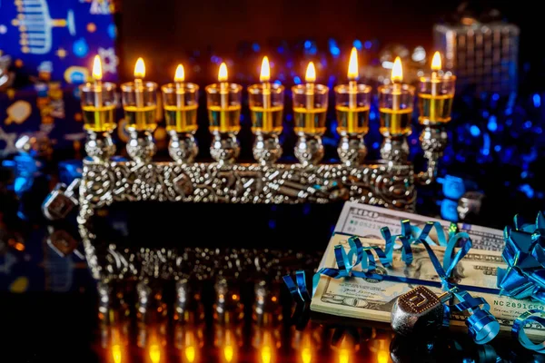 Dollar bill with burning menorah with reflection for Hanukkah. Jewish holiday.