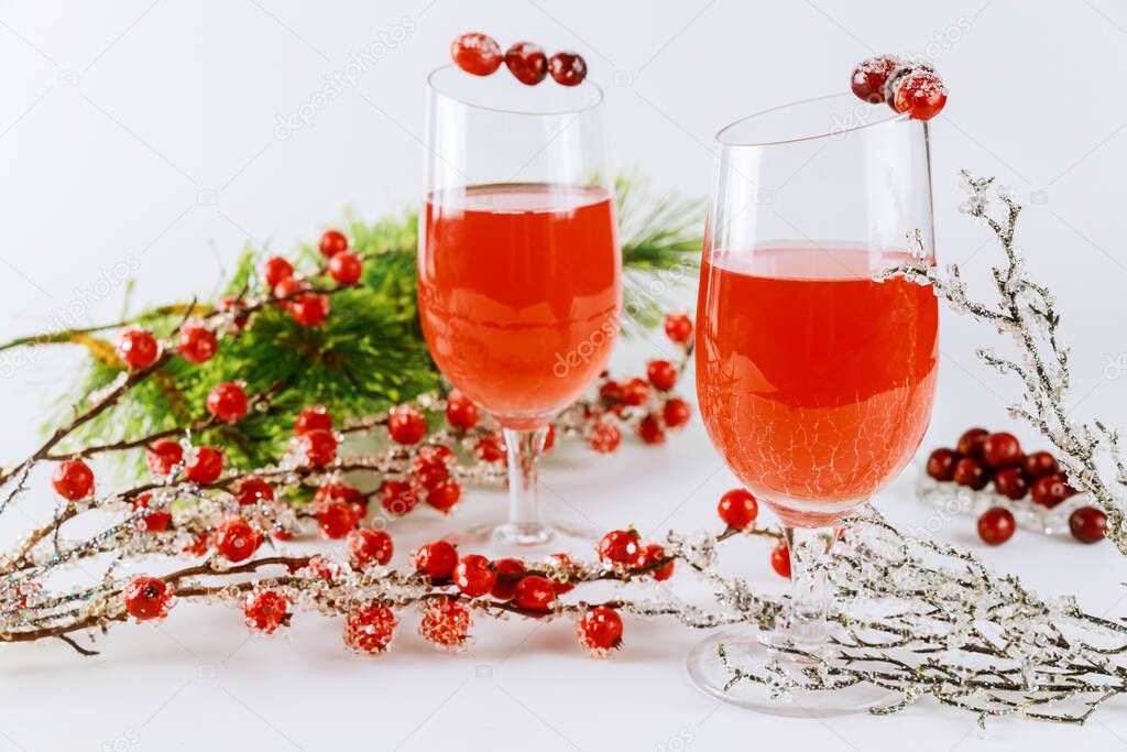 Festive cranberry cocktail with red berries decoration on white background. Christmas background.