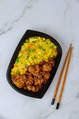 Susamlı tavuklu teriyaki, pilav ve çubuk. Yemek teslimatı.