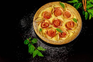 Yeşil yapraklı ve tarçınlı siyah arka planda güzel ev yapımı elmalı turta..