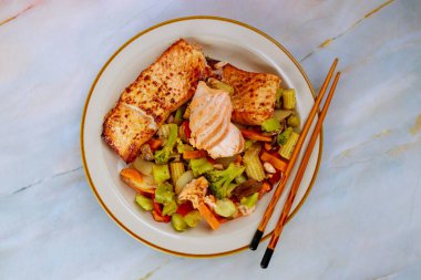 Asya usulü kızarmış sebzeli pembe somon filetosu. Üst görünüm.