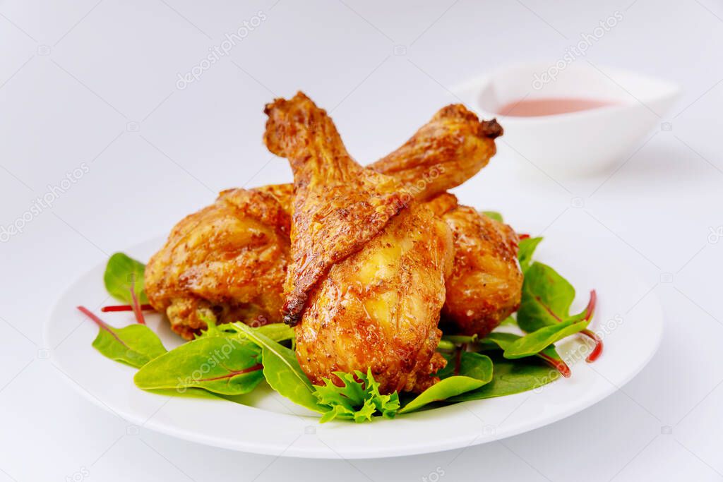 Roasted spicy chicken drumstick with salad on white background. Close up.