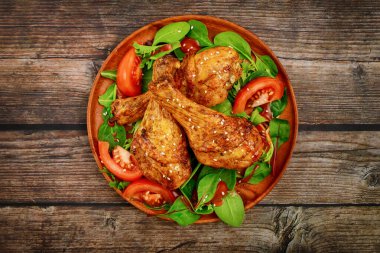 Baked chicken drumsticks with salad on rustic wooden background, Close up. Top view. clipart