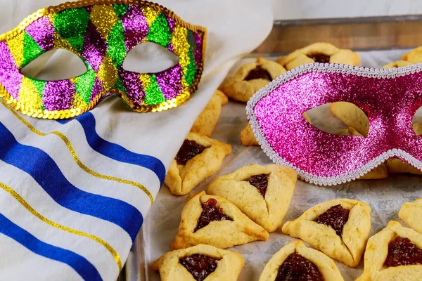 Traditional hamantaschen jewish cookies with jam, tallit and mask for Purim. Jewish holiday.