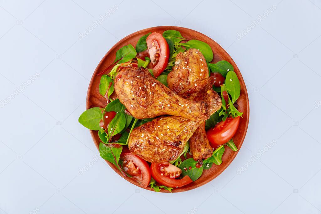 Roasted spicy chicken drumstick with salad on white background. Top view.