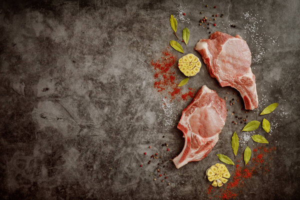 Fresh pork chops rib and spices on gray background with copy space. Top view.