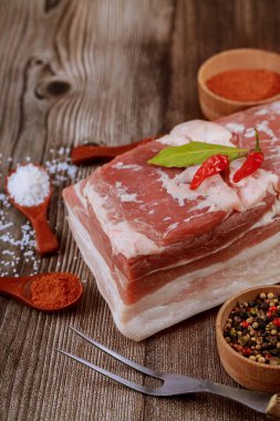 Baharat ve bitkilerle ahşap arka planda çiğ domuz eti parçalarını kapatın..