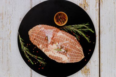 Kemiksiz domuz omuzu ve siyah tahta üzerinde baharatlar. Tatil yemeği..