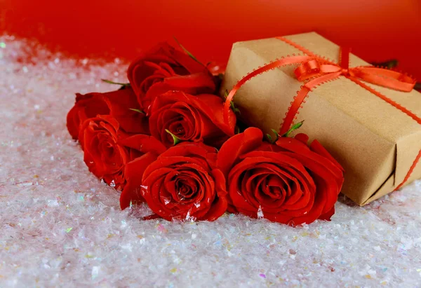 Gift box and bouquet of beautiful red roses on sparkle snow. Mother\'s Day or Valentine\'s Day concept..