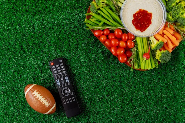 Party table with remote control for sport watching american football game on tv.