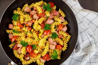 Renkli makarna rotini, kirazlı domates ve tavada jambon. Kapatın. Üst görünüm.