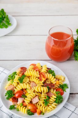 Rotini makarna, jambon ve sebze ve bir bardak domates suyu. Dengeli yemek.