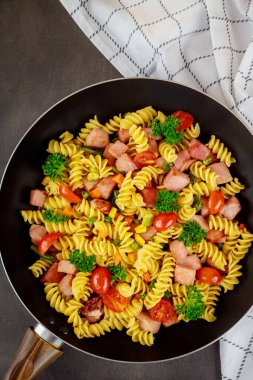 Renkli makarna rotini, kirazlı domates ve tavada jambon. Kapatın. Üst görünüm.