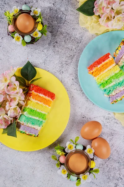 Colorful cut cake with brown eggs for Easter on wooden background.