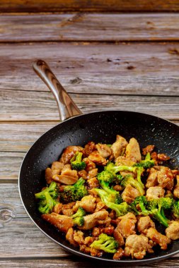 Baharatlı tavuklu teriyaki, ahşap arka planda brokoli var..