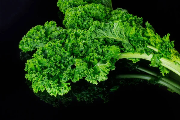 Fresh green kale leaves on black isolated background.