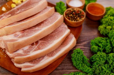 Tahtada deri, baharat ve otlarla dilimlenmiş çiğ domuz omuzu..