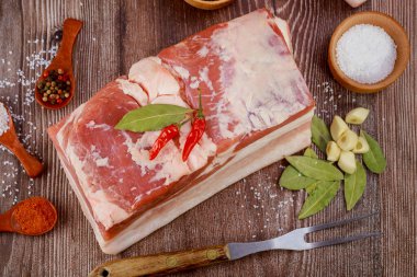 Bir parça sarımsaklı domuz göbeği ve ahşap arka planda defne yaprakları..