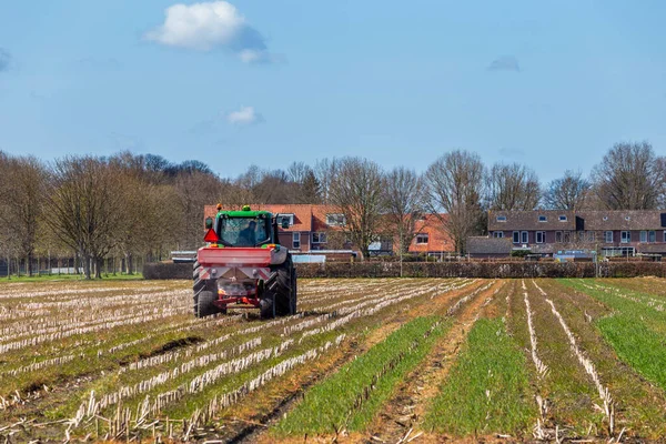 Landschaft mit Bauer auf Traktor, der sein Land düngt — Stockfoto