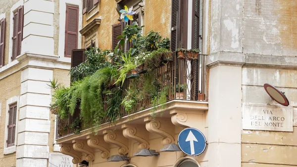 Balkong med blommor på en gammal gul lägenhet byggnad i Rom — Stockfoto