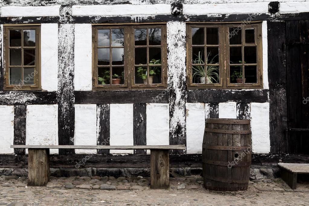 White timbered house, with  a bench and rainbarrel  in the old t