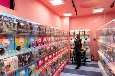 Tokyo, Japonya - 14 Mart 2025: Japonya 'da Japon Gashapon ile aydınlatma dükkanında ağız şapkalı Japon kadın. Gachapon kapsüllü oyuncaklar dağıtan satış makineleridir..