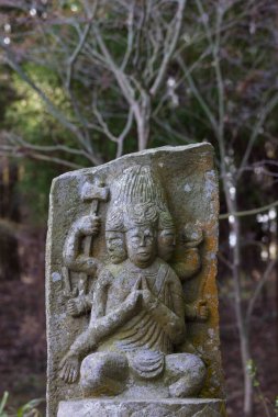 Üzerinde Murti figürü olan küçük yıpranmış Buda heykeli plaketi Japonya 'daki küçük bir köy olan Aso Kumamoto' daki Saigandenji Tapınağı 'nda farklı güçleri sembolize eden çeşitli yüz ve kollara sahip.