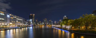 Japonya 'nın Osaka kentindeki Temmabashi mahallesindeki aydınlık binalar ve yollarla akşam saatlerinde şehir manzarası manzarası