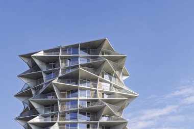 Danimarka 'nın Kopenhag kentindeki heykel kulesi, uzaktaki balkonlarla dinamik geometri yaratır. Parlak cam cephe güneş ışığını yansıtır, yeşillik ve yol kenarında geçer. Mimarlık, tasarım ve kentsel dönüşüm temaları için ideal.