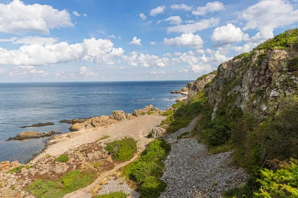 Danimarka 'daki Hovs Hallar Doğa Koruma Alanında kayalık uçurumlar, bir çakıl taşı plajı ve sakin bir mavi deniz içeren dramatik bir kıyı manzarası..