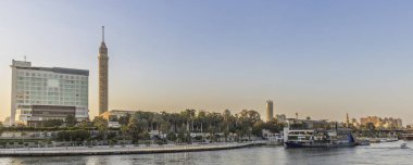 Mısır 'daki Caior siluetinin panoramik görüntüsü Kahire kulesi, Nil boyunca çağdaş oteller ve tekneler, kentsel sıcak, güneşli atmosferi yakalıyor..